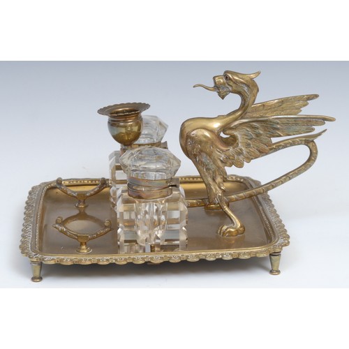 1264 - A 19th century brass inkstand, the handle cast as a wyvern, the square cut glass wells centred by a ... 