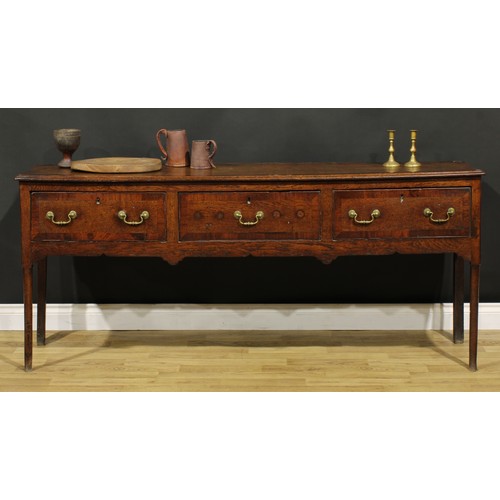 1305 - A George III mahogany crossbanded oak low dresser, slightly oversailing top above three frieze drawe... 