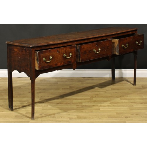 1305 - A George III mahogany crossbanded oak low dresser, slightly oversailing top above three frieze drawe... 