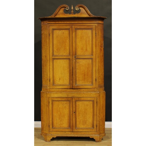 1526 - A 19th century pine floor-standing corner cupboard, scumbled as oak, swan neck pediment above a pair... 