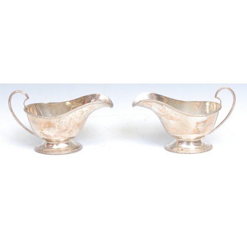 674 - A pair of George V silver pedestal sauce boats, 15.5cm long, Walker and Hall, Sheffield 1929; a pair... 