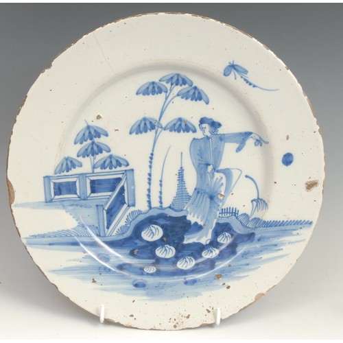 109 - An 18th century Delft circular plate, painted in the chinoiserie taste with a figure in a Chinese ga... 