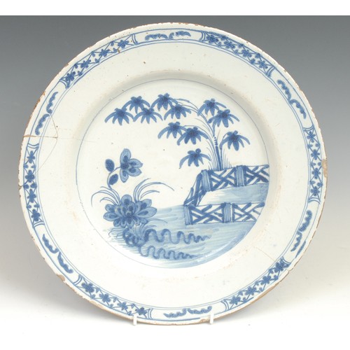 104 - An 18th century Delft circular dish, painted in the Chinese taste with a pagoda in a landscape, 31cm... 