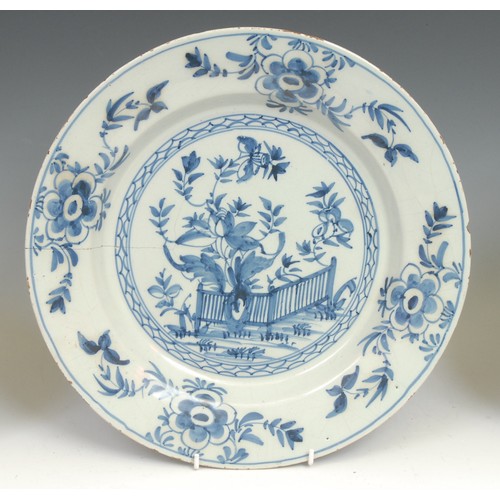 105 - An 18th century Delft circular dish, painted in tones of blue in the Chinese taste with a flowering ... 