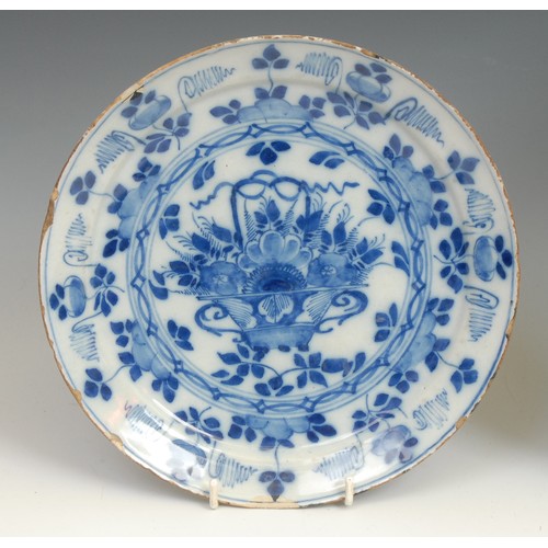 105 - An 18th century Delft circular dish, painted in tones of blue in the Chinese taste with a flowering ... 