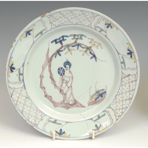 107 - An 18th century Delft circular plate, painted in the Chinese taste with a lady in a garden, 21.5cm d... 