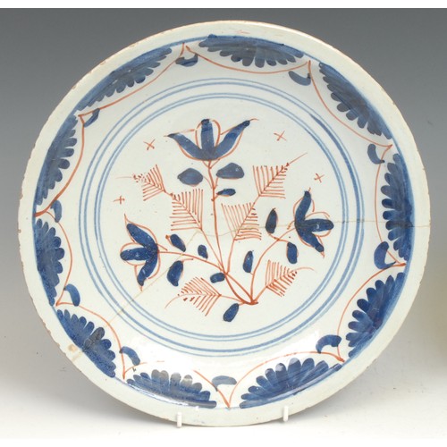 107 - An 18th century Delft circular plate, painted in the Chinese taste with a lady in a garden, 21.5cm d... 