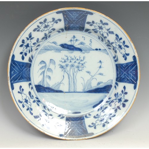 97 - A large 18th century Delft circular charger, painted in the Chinese taste with a pine tree and chrys... 