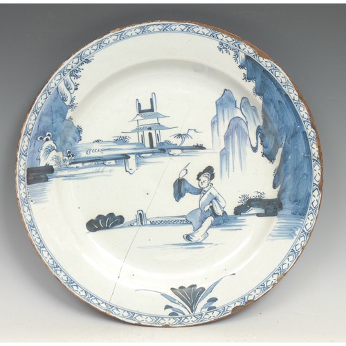 97 - A large 18th century Delft circular charger, painted in the Chinese taste with a pine tree and chrys... 