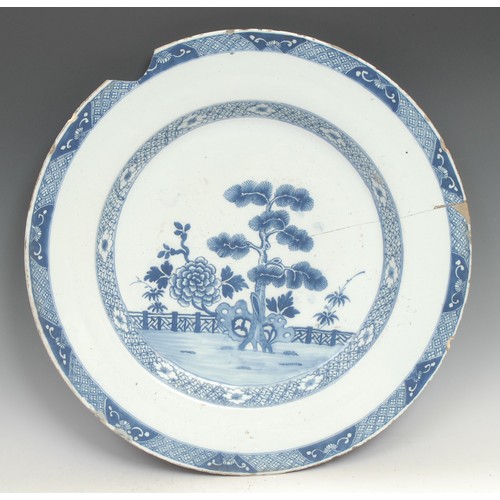 97 - A large 18th century Delft circular charger, painted in the Chinese taste with a pine tree and chrys... 