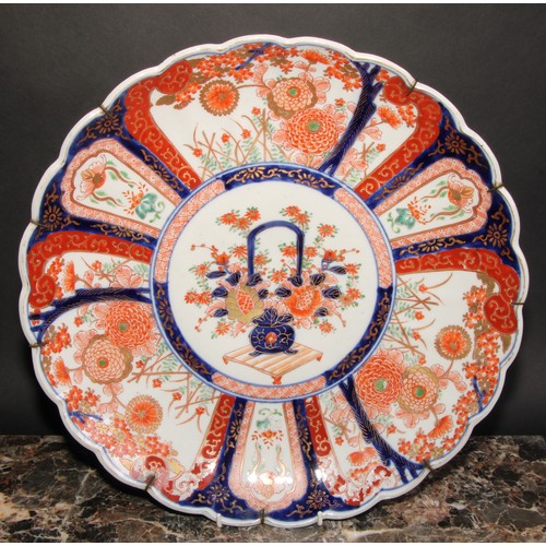 424 - A Japanese scalloped circular charger, painted in the Imari palette with central floral vase within ... 