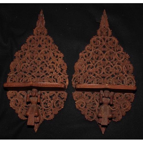 2136 - A pair of Burmese hardwood wall brackets, pierced and profusely carved with scrolling foliage, each ... 