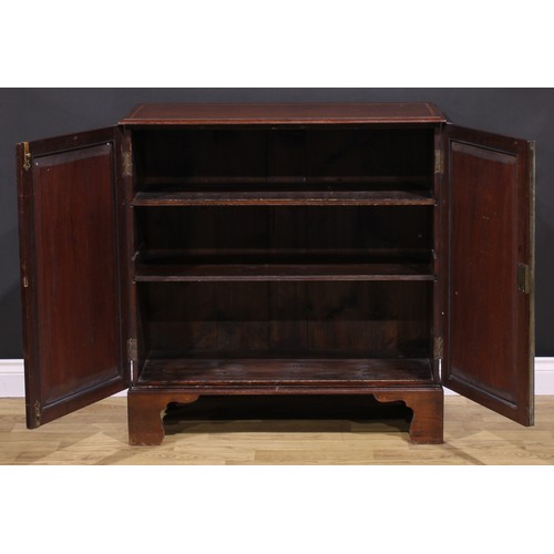 1245 - A 19th century mahogany enclosed bookcase, oversailing top above a pair of panel doors enclosing adj... 