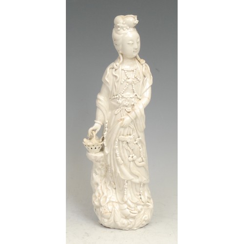 385 - A Chinese blanc de chine figure, Guanyin, she stands, holding a basket, 26cm high, 18th century