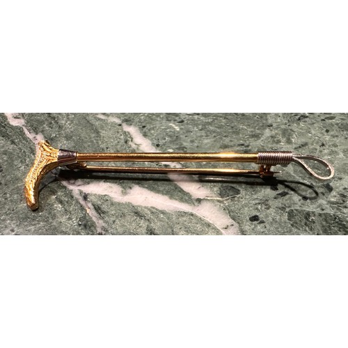 866 - A gold coloured metal bar brooch as a rifle with gun dog to fore, ruby chip eye, stamped '9ct' for 9... 