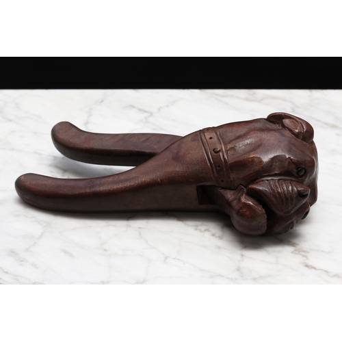 2232 - Nutcrackers - a Black Forest novelty lever-action nut cracker, carved as the head of a bulldog, glas... 