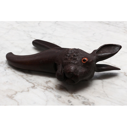 2274 - Nutcrackers - a Black Forest novelty lever-action nut cracker, carved as the head of a hare, glass e... 