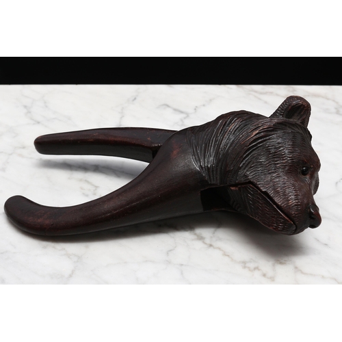 2267 - Nutcrackers - a Black Forest novelty lever-action nut cracker, carved as the head of a bear, glass e... 