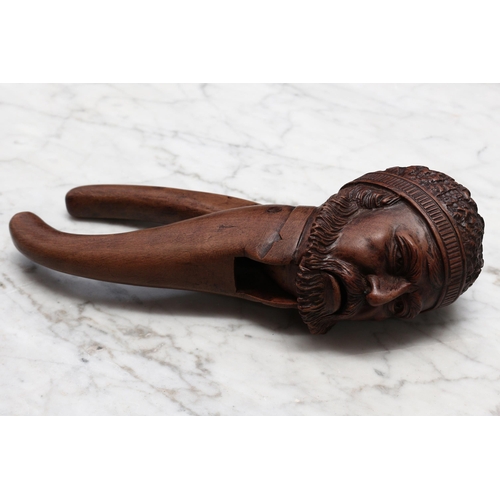 2290 - Nutcrackers - a Continental walnut novelty lever-action nut cracker, carved as the head of a bearded... 