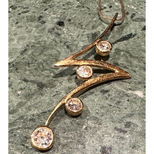 923 - A diamond and gold coloured metal lightening bolt pendant, bezel set with four round brilliant cut s... 