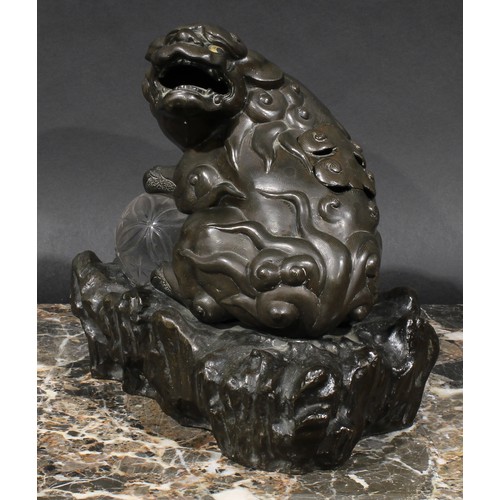 436 - A Chinese brown patinated bronze censer and cover, cast as a temple lion, his paw resting on a glass... 