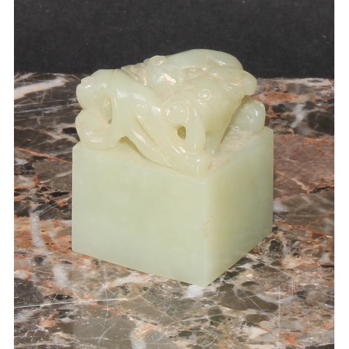 438 - A Chinese celadon jade seal, carved with an archaic ox, 3.5cm high