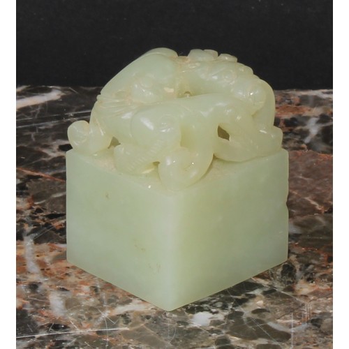 438 - A Chinese celadon jade seal, carved with an archaic ox, 3.5cm high