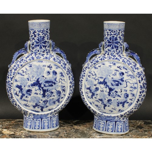 430 - A pair of Chinese moon flasks, painted in tones of underglaze blue with temple lions, on a ground of... 