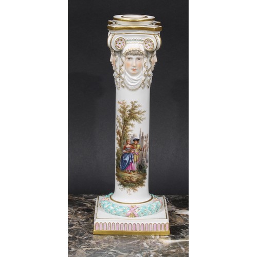 268 - A pair of Meissen columnar candlesticks, each moulded with masks and painted with a courting couple,... 