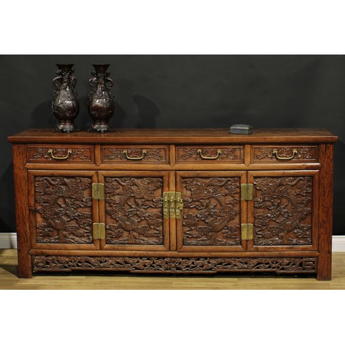 1295 - A Chinese hardwood side cabinet, rectangular top above four drawers and four panel doors, each carve... 