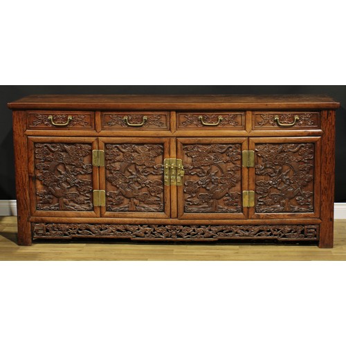 1295 - A Chinese hardwood side cabinet, rectangular top above four drawers and four panel doors, each carve... 