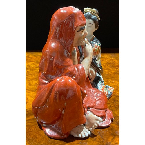 462 - A Japanese porcelain figure group, as a seated robed monk with Geisha attendant cleansing his ear, p... 