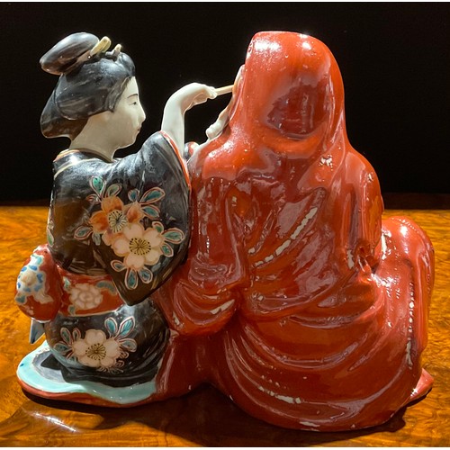 462 - A Japanese porcelain figure group, as a seated robed monk with Geisha attendant cleansing his ear, p... 