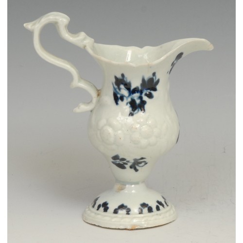 182 - A Liverpool pedestal cream jug, moulded with flowers, decorated in underglaze blue with floral sprig... 