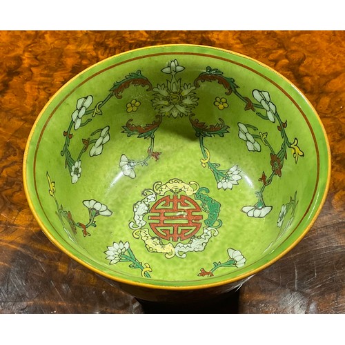 390 - A Chinese circular bowl, decorated in polychrome enamels with flowers and symbol on an apple green g... 