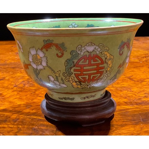 390 - A Chinese circular bowl, decorated in polychrome enamels with flowers and symbol on an apple green g... 