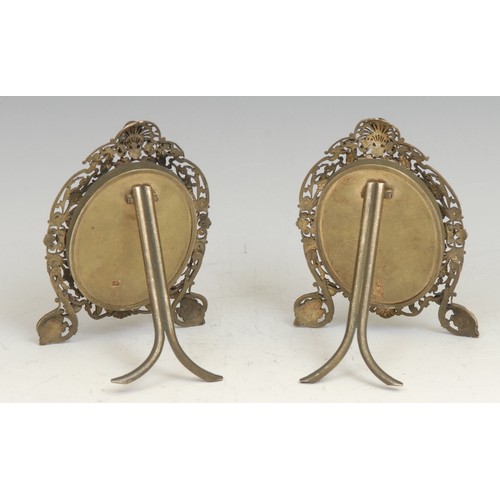 1216 - A pair of 19th century silvered metal easel photograph frames, the pierced leafy scroll frames appli... 