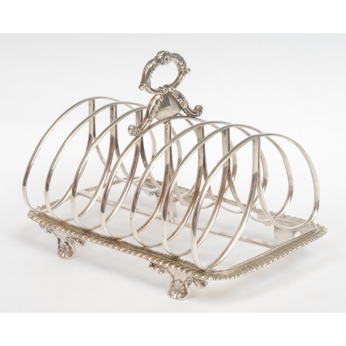 771 - An early Victorian silver seven-bar toast rack, twin-loop divisions, leafy loop handle, gadrooned bo... 