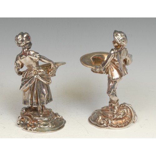 521 - A pair of Rococo Revival silver plated figural salts, cast as a fisher boy and girl holding baskets,... 