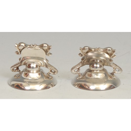 676 - A pair of Victorian silver novelty menu holders, each with a pair of dolphins, domed circular bases,... 