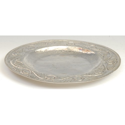 753 - An Arts and Crafts silver circular charger, planished overall and chased with a border of fruiting o... 