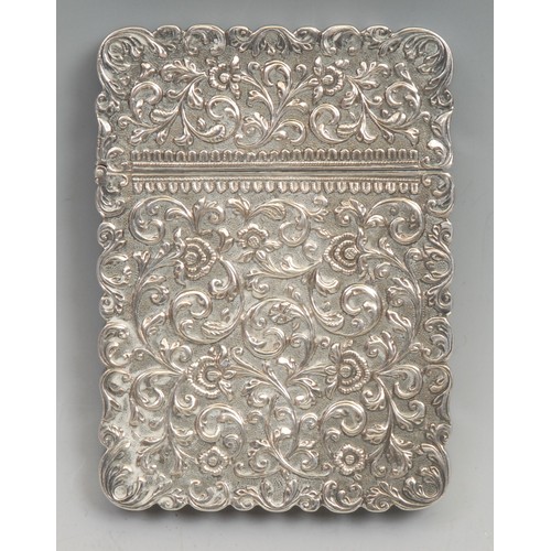 813 - An Indian silver shaped rectangular visiting card case, profusely chased with scrolling lotus, push-... 