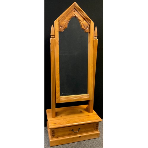 101 - A Gothic style pine Cheval mirror, the mirror having a carved Gothic arch top, single drawer to base... 