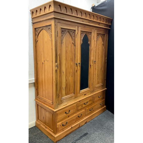 103 - A Gothic style pine triple wardrobe, central dressing mirror door, flanked by a pair of doors with G... 