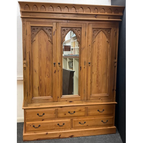 103 - A Gothic style pine triple wardrobe, central dressing mirror door, flanked by a pair of doors with G... 