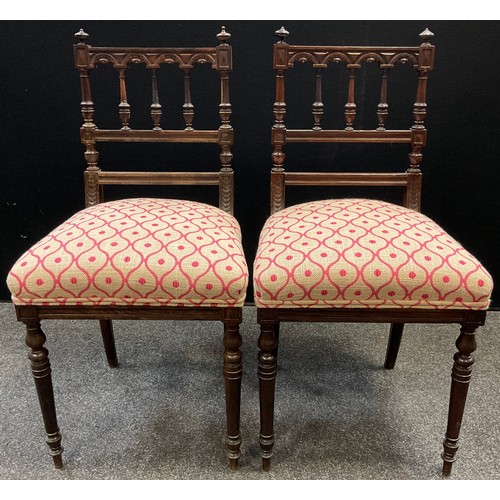 275 - A pair of Edwardian carved Rosewood bedroom chairs, spindle backs, 84cm high, (2).