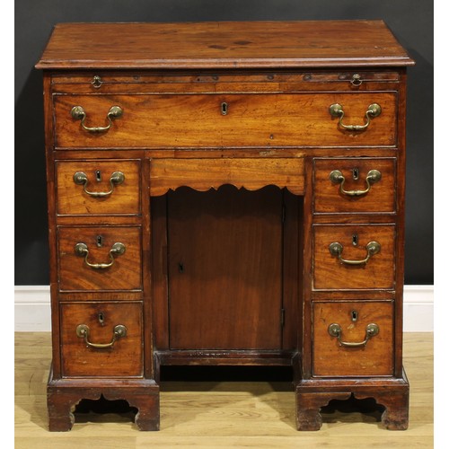 1228 - A George III mahogany kneehole desk, the ovolu moulded top above a brushing slide, axe head handles,... 