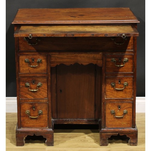 1228 - A George III mahogany kneehole desk, the ovolu moulded top above a brushing slide, axe head handles,... 