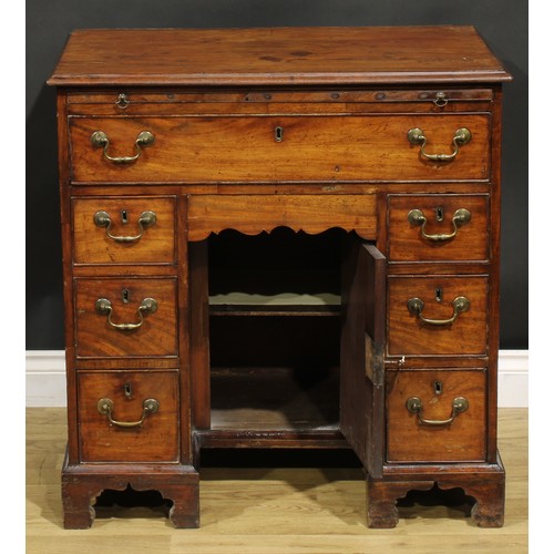 1228 - A George III mahogany kneehole desk, the ovolu moulded top above a brushing slide, axe head handles,... 