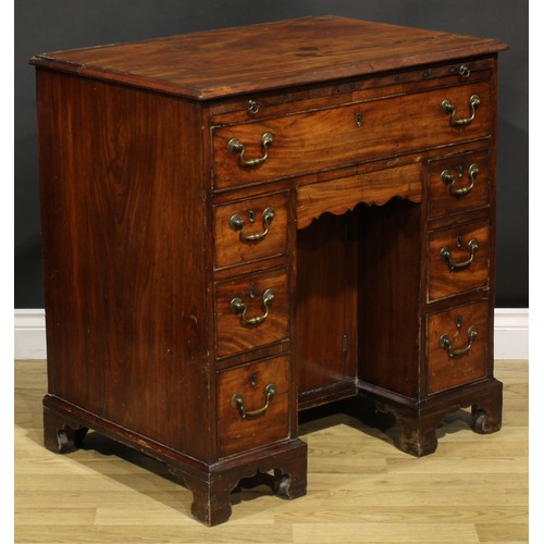 1228 - A George III mahogany kneehole desk, the ovolu moulded top above a brushing slide, axe head handles,... 